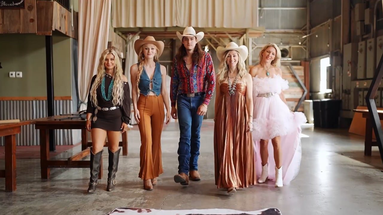 Models in western wear lined up in a barn for an event film